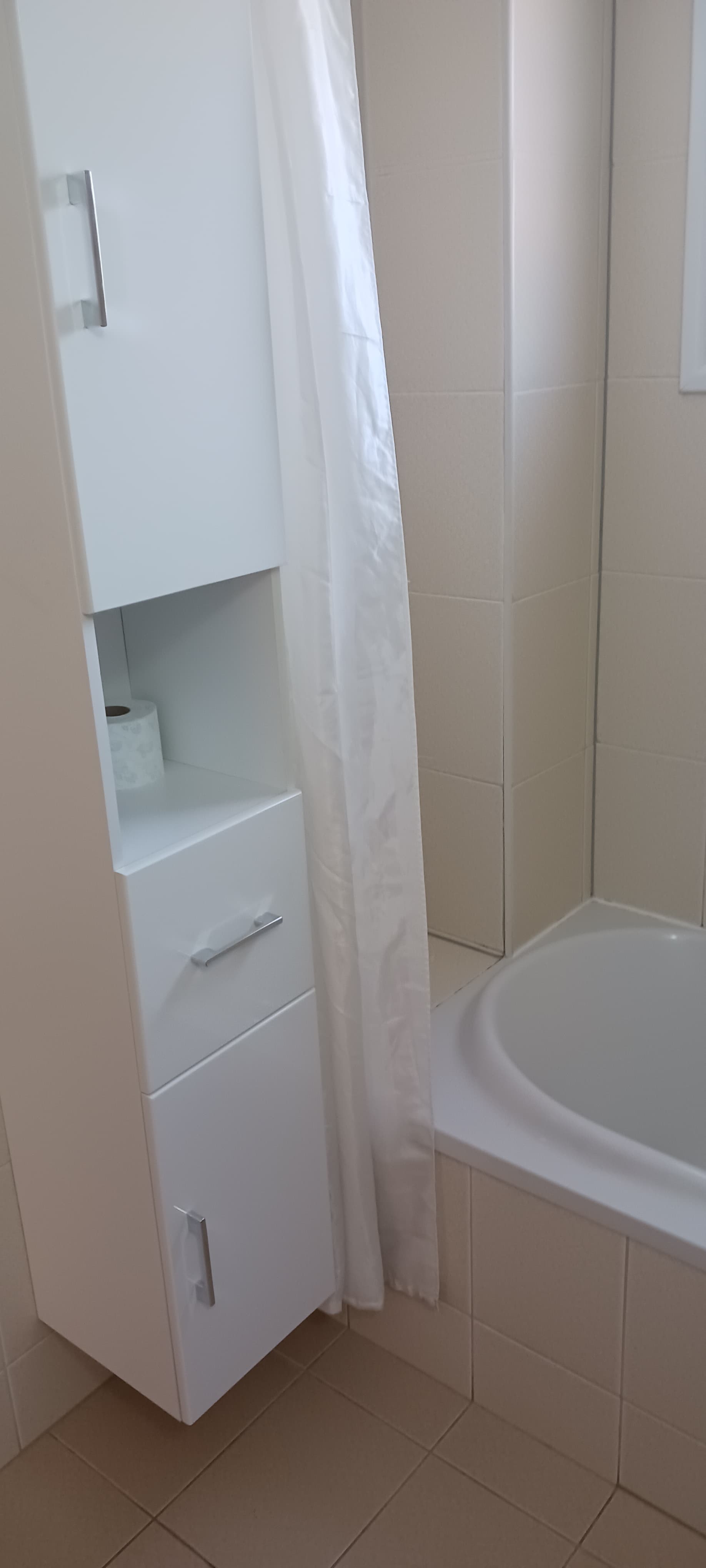 Clean tiled bathroom with a bathtub and shower
