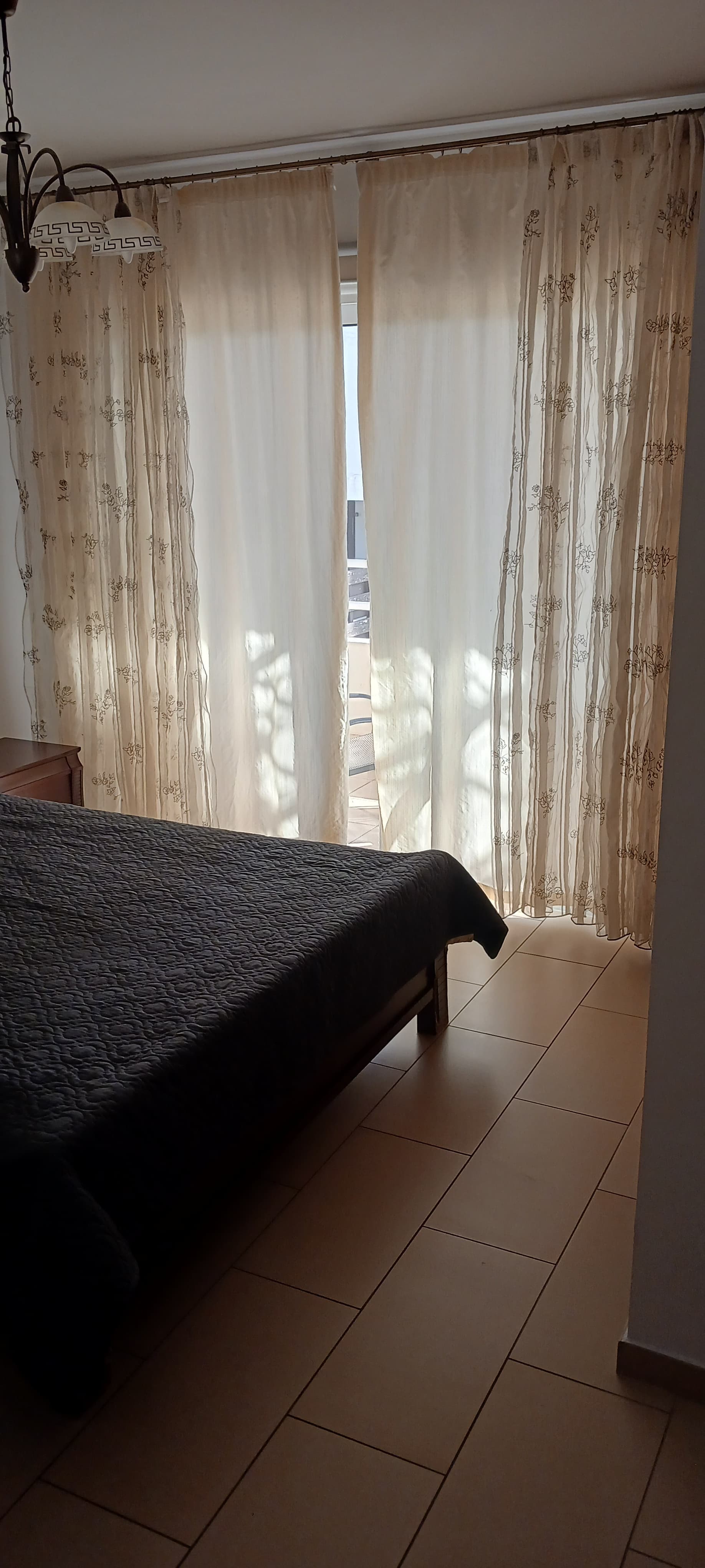 Main bedroom with a double bed and soft natural light through the curtains