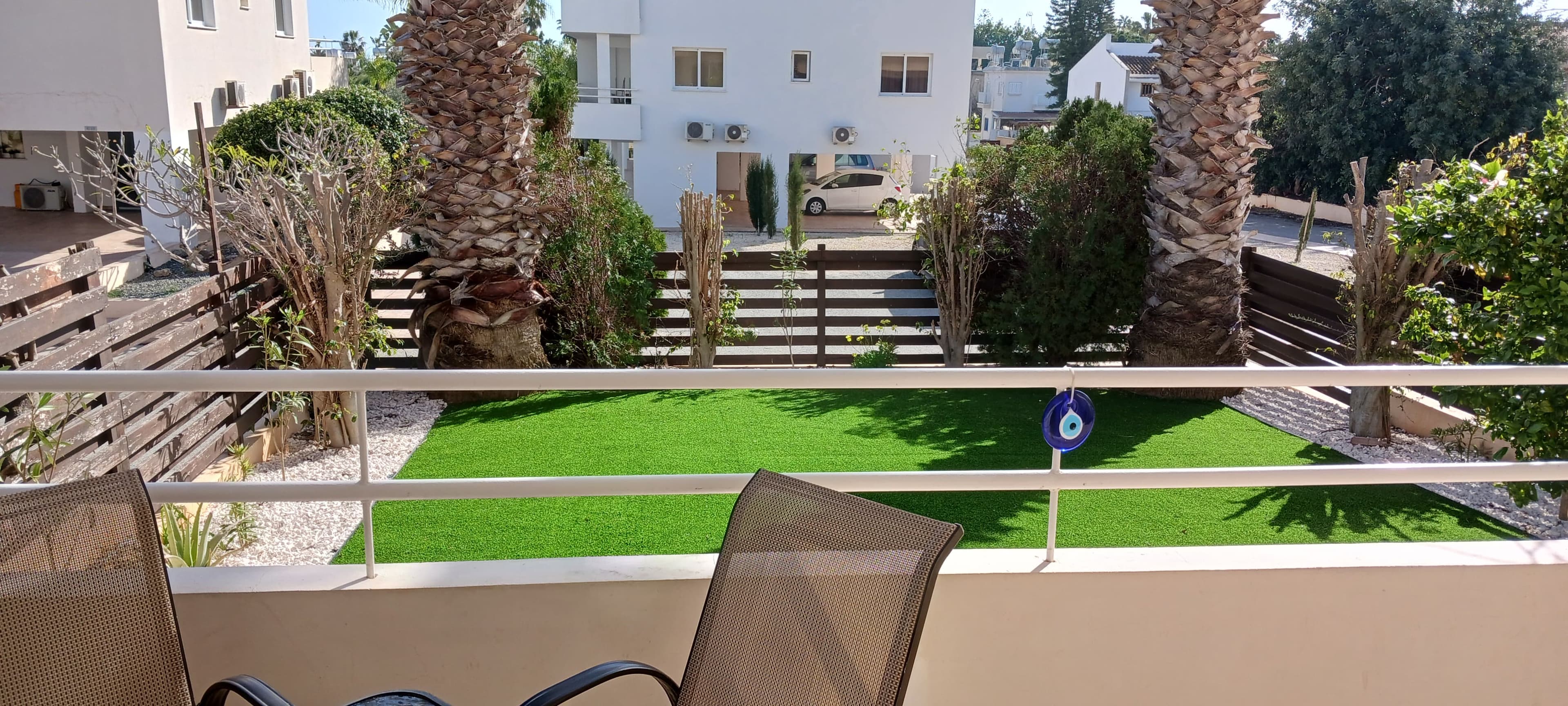 Private green lawn garden framed by palm trees at the Nissi 3 complex