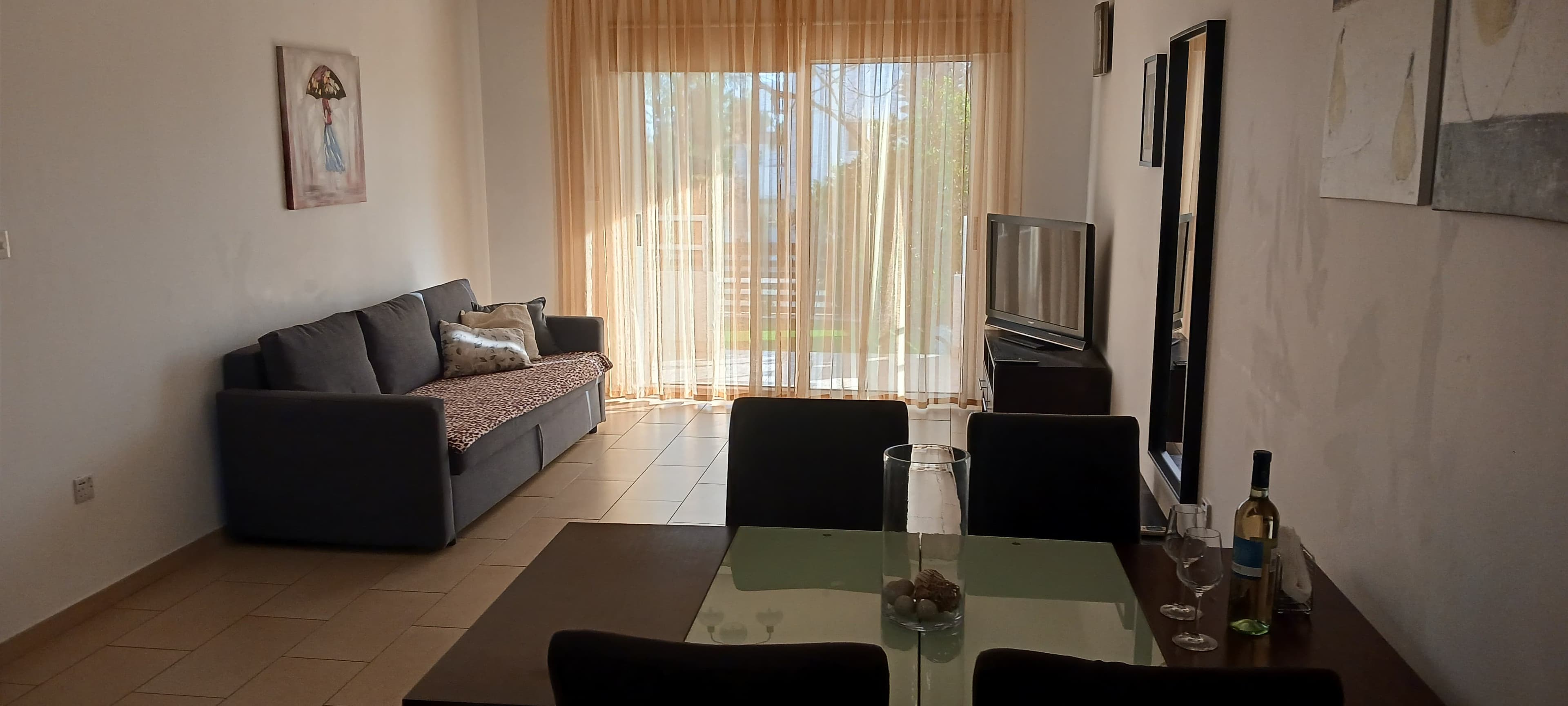 Open-plan living room with a grey sofa, dining table and sliding doors to the terrace