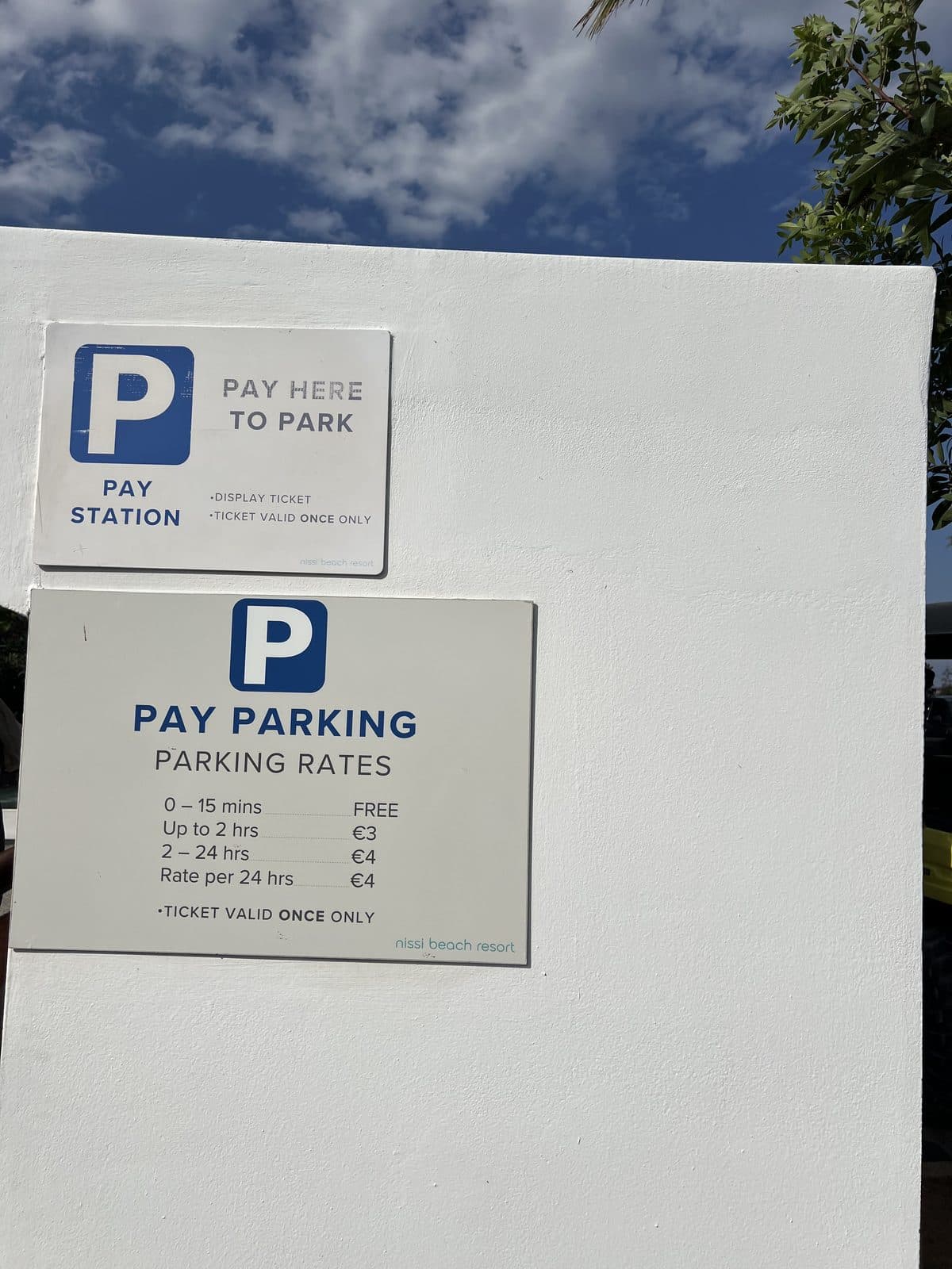 Pay parking rate board at Nissi Beach, July 2026, showing €3 up to 2 hours and €4 for 2–24 hours